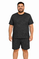 Homem usando pijama masculino curto em tecido suede preto estampado, com camiseta de manga curta, gola V e bermuda soltinha.