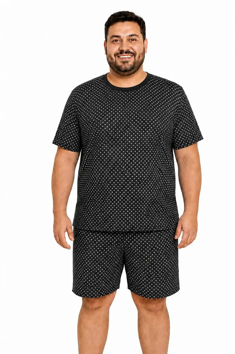 Homem usando pijama masculino curto em tecido suede preto estampado, com camiseta de manga curta, gola V e bermuda soltinha.