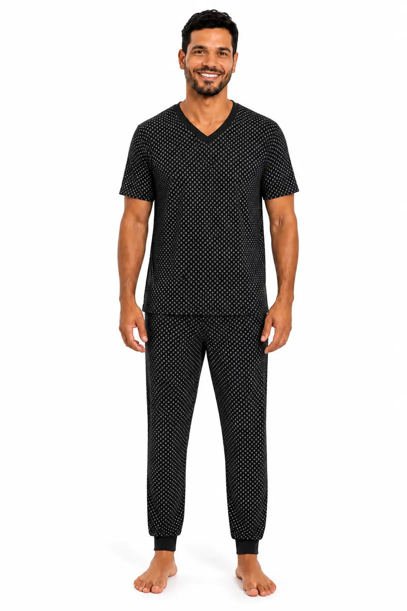 Homem usando pijama masculino longo preto estampado em tecido suede, com camiseta de manga curta, gola V e calça sem bolsos com punhos.
